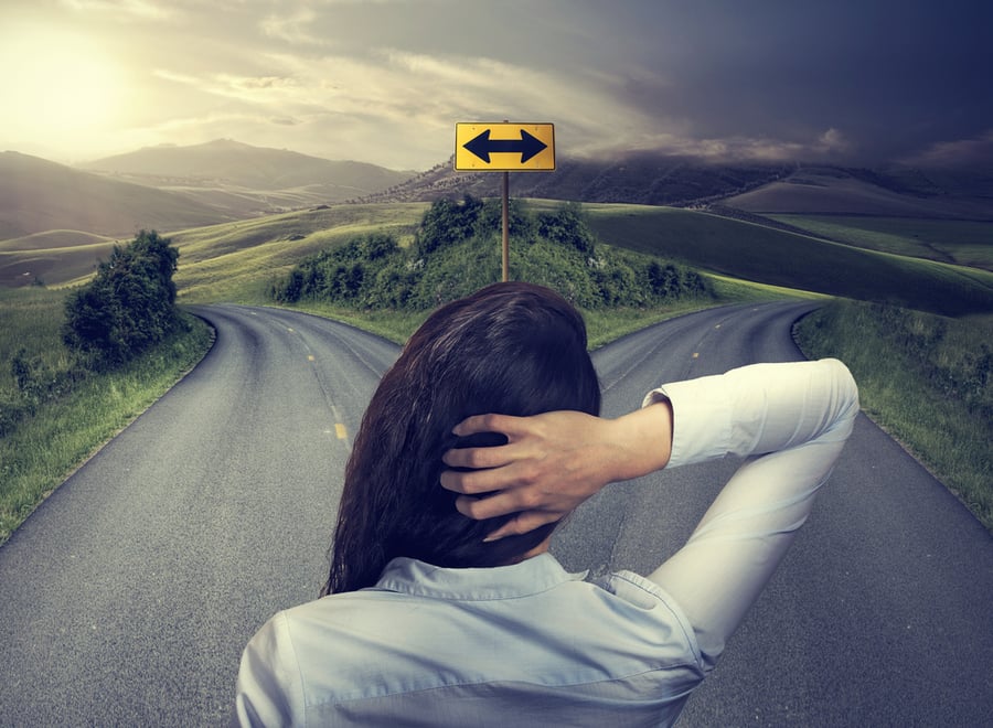 business woman in front of two roads thinking deciding hoping for best taking chance